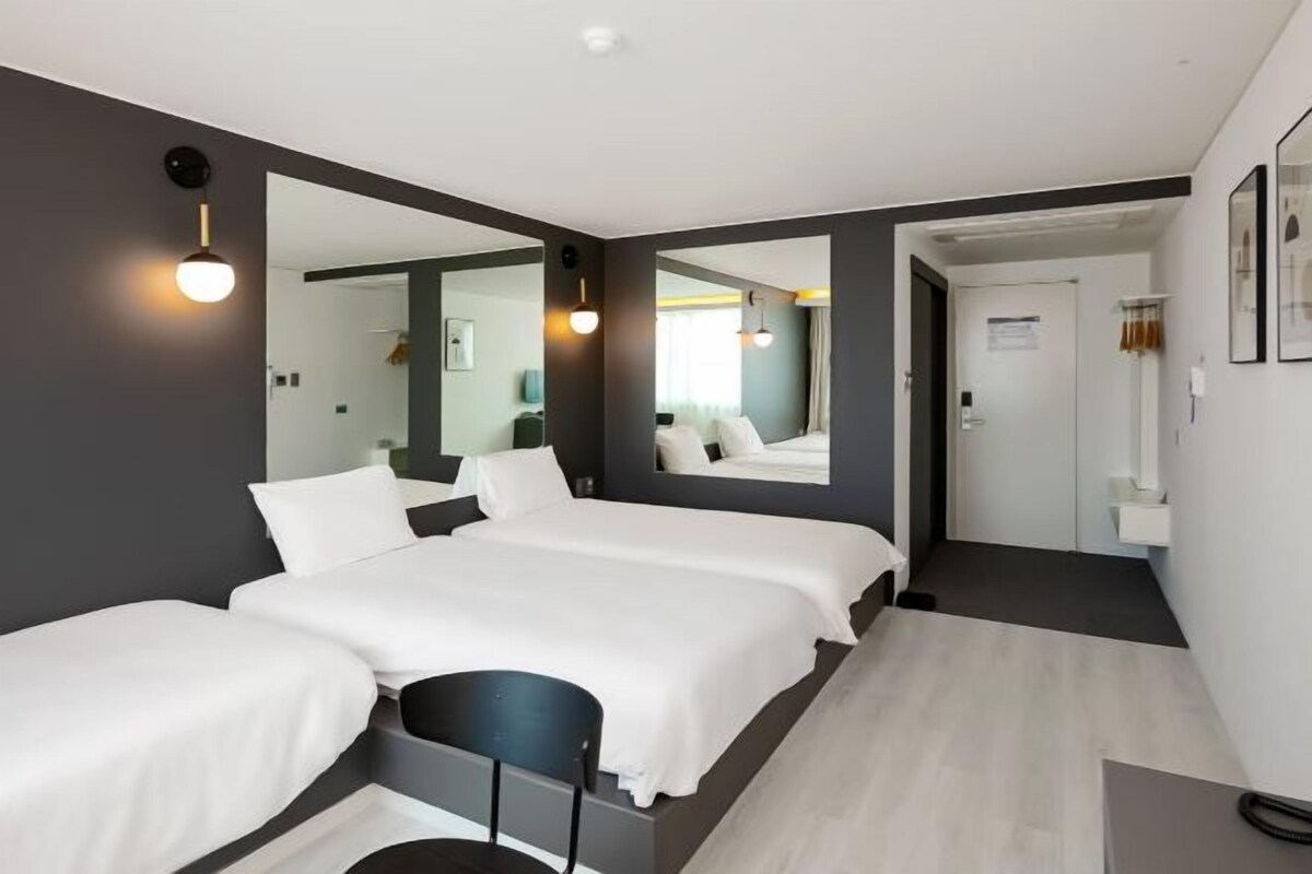 Une chambre d’hôtel moderne avec un grand lit, un petit bureau et un miroir.