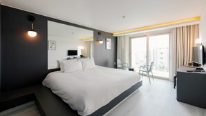 A modern hotel room with a large bed, a desk with a computer, a TV, and a balcony with curtains. - Pampas Hotel Jeju (Jeju City)