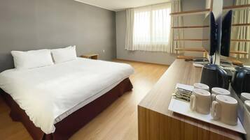 A hotel room with a large bed, a desk with a computer, and a TV.
