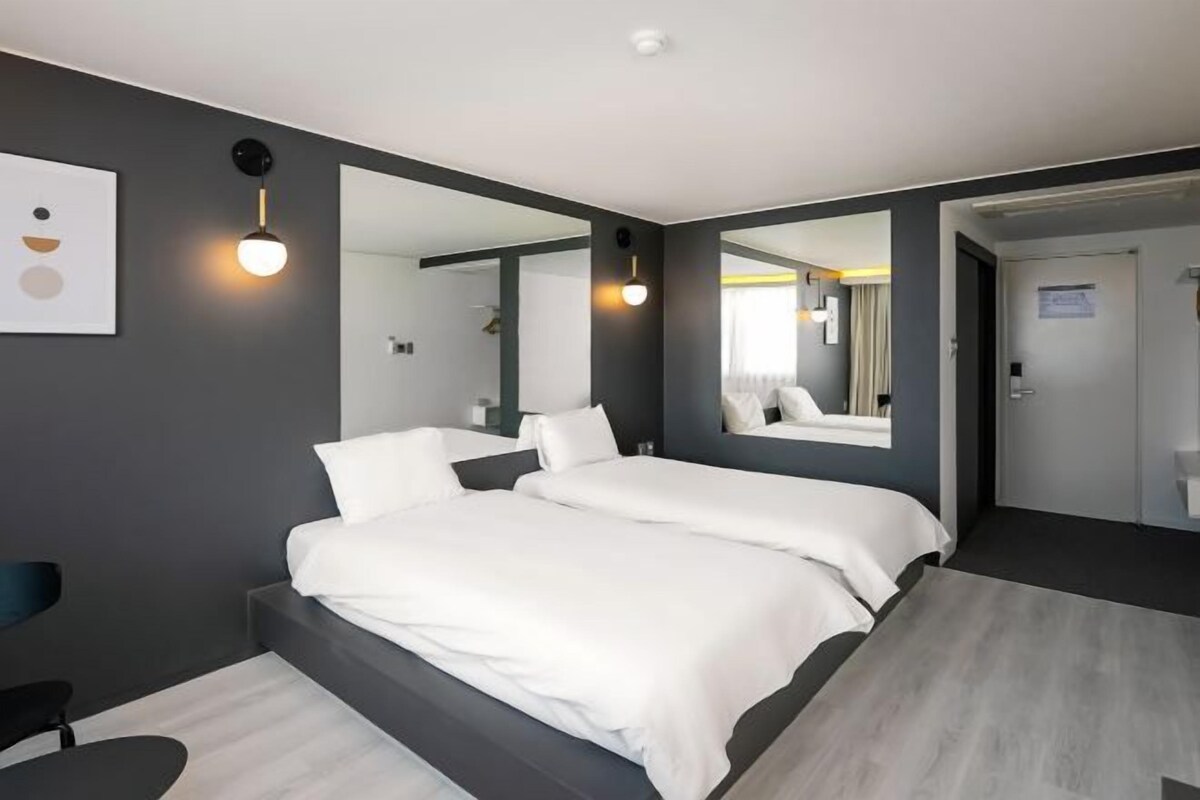 Ein modernes Hotelzimmer mit einem großen Bett, einem Schreibtisch und einem Spiegel.