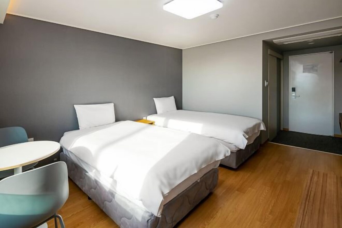 Ein Hotelzimmer mit zwei Betten, einem kleinen runden Tisch und einem Stuhl.