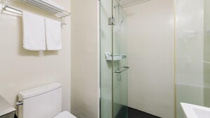 A bathroom with a toilet, a glass shower enclosure, and a towel rack. - Pampas Hotel Jeju (Jeju City)
