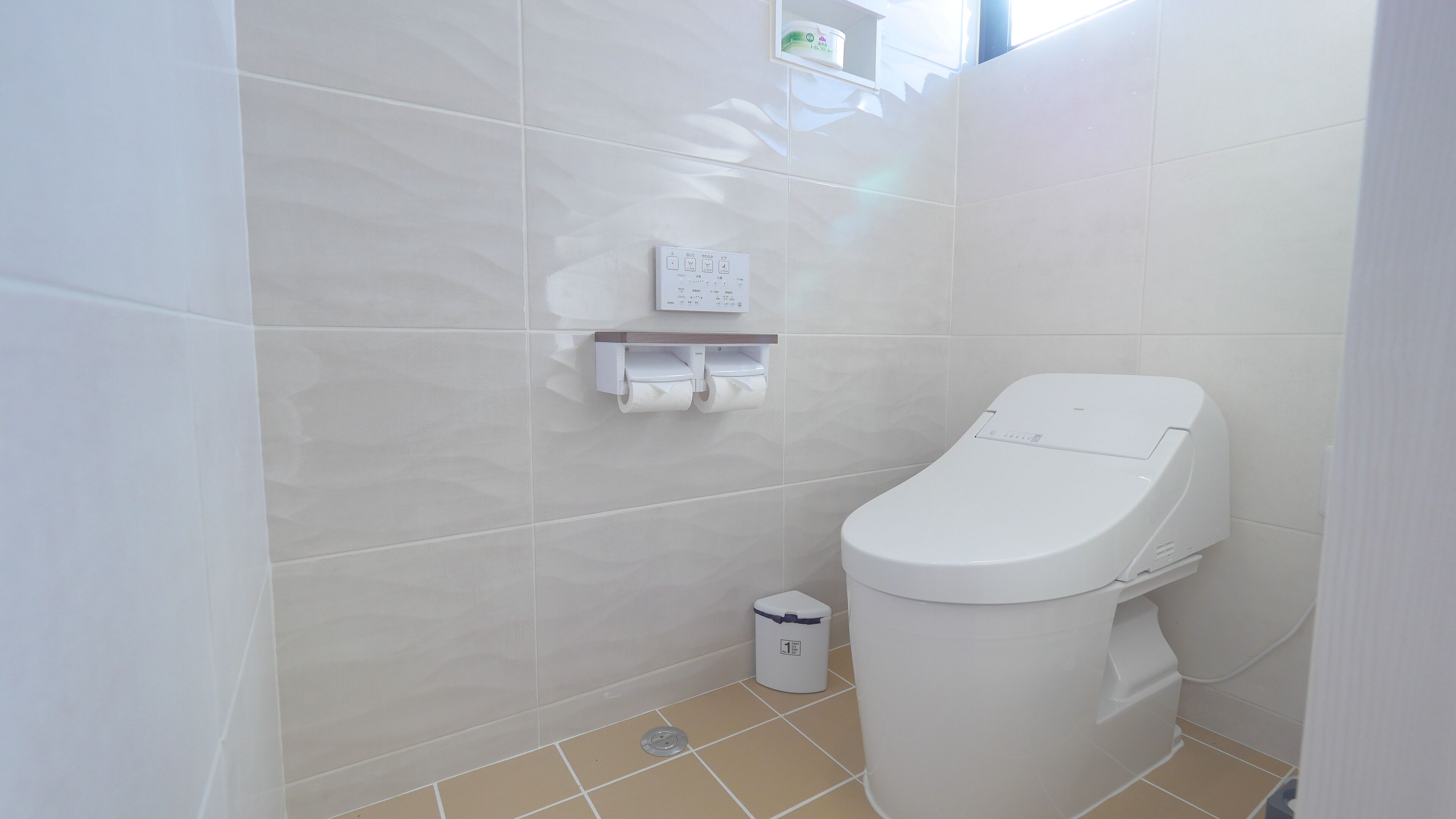 Een moderne badkamer met toilet, handdroger en afvalbak.