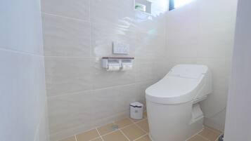 Een moderne badkamer met toilet, handdroger en afvalbak.