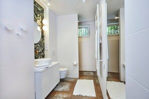 A modern bathroom with white tiles, a white sink, a toilet, and a mirror with lights. - Large holiday home, summer pool, sauna, whirlpool (Sasino)
