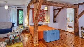A room with wooden beams, a bed, a chair, a small table, and a window with curtains. - Large holiday home, summer pool, sauna, whirlpool (Sasino)