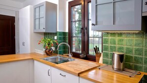 A kitchen with white cabinets, a wooden countertop, a sink, a window with a view, and a kettle. - Large holiday home, summer pool, sauna, whirlpool (Sasino)