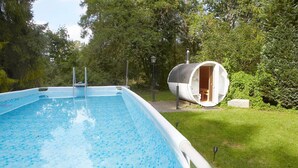 A swimming pool with a small wooden deck and a cylindrical building with a door, surrounded by lush greenery. - Large holiday home, summer pool, sauna, whirlpool (Sasino)