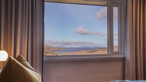 A room with a bed, a window with a view of a landscape, and curtains. - The West Nest -Luxury Cottage, Sea Views & Hot Tub (Isle of Skye)