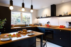 Une cuisine moderne dotée d’un plan de travail en bois, d’un four encastré et d’une fenêtre laissant entrer la lumière naturelle.