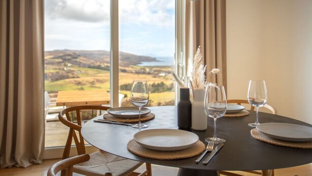 A dining table set for four with a view of the countryside. - The West Nest -Luxury Cottage, Sea Views & Hot Tub (Isle of Skye)