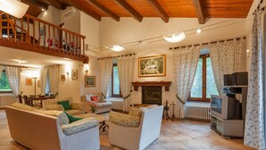 Un salon spacieux avec une cheminée, un téléviseur et un balcon.