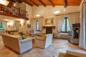 A spacious living room with a fireplace, a television, and a balcony.