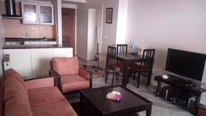 A living room with a sofa set, a coffee table, a TV, and a dining area with chairs and a table. - S+1 in the tourist zone (Sousse)