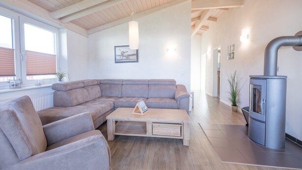 A modern living room with a sectional sofa, a coffee table, a fireplace, and a large window.