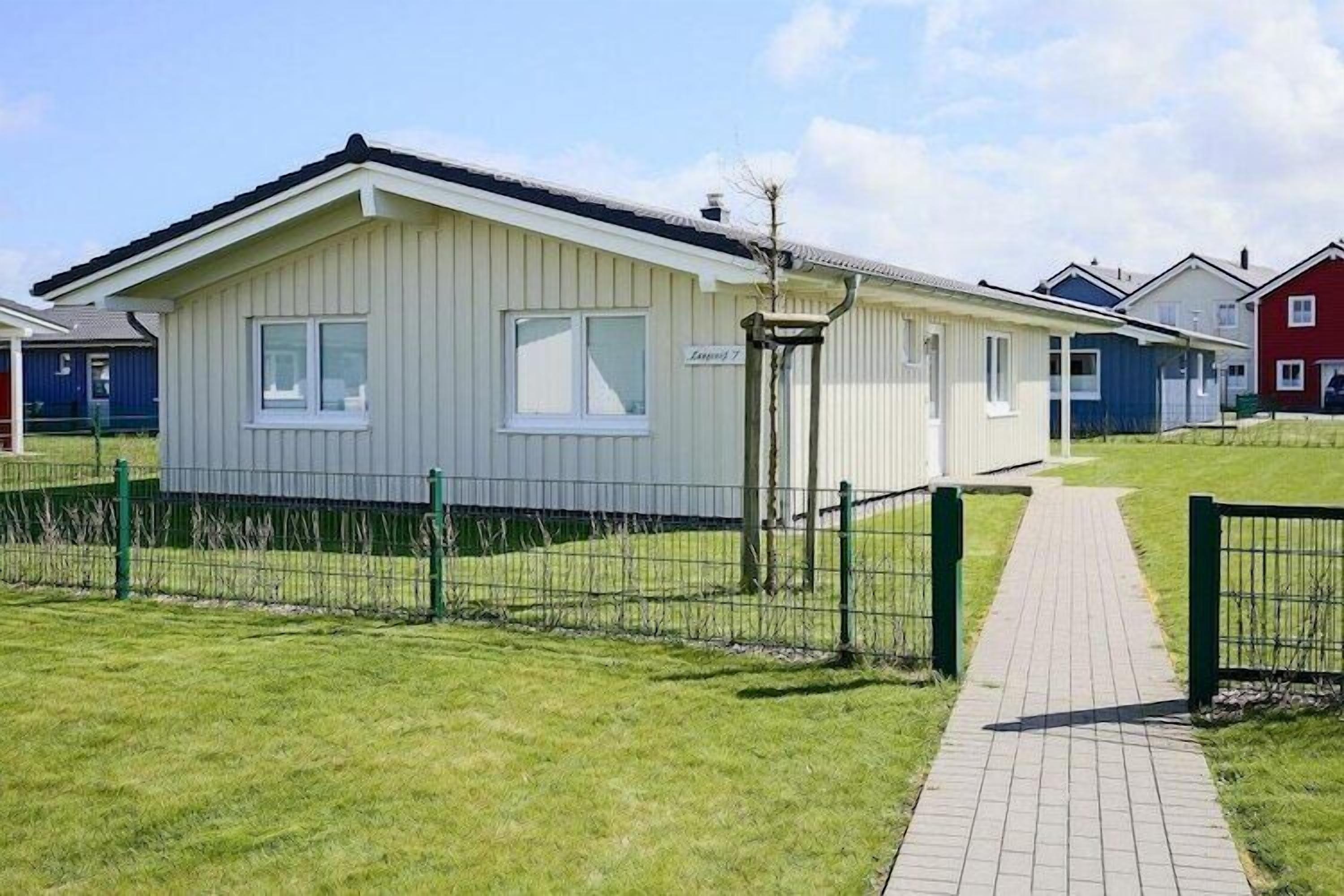 A row of single-story mobile homes with a paved walkway leading to the entrance.