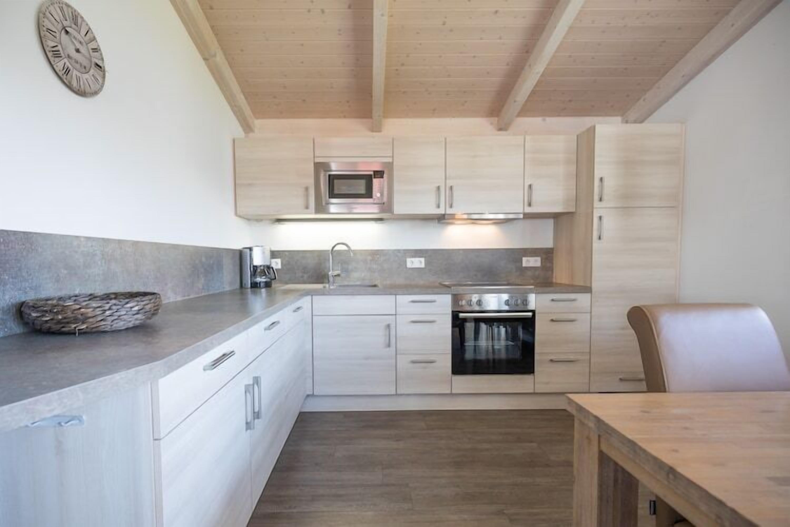Eine moderne Küche mit hellen Holzschränken, einer Edelstahl-Mikrowelle und einem eingebauten Ofen.