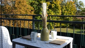 A table with a vase, a glass, and a cup on a balcony with a railing. - "Kleine Auszeit" Helle Ferienwohnung mit Balkon, mitten im Zentrum (Burg (Spreewald))