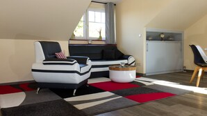 A modern living room with a sectional sofa, a black and white armchair, a coffee table, and a red and black rug. - "Kleine Auszeit" Helle Ferienwohnung mit Balkon, mitten im Zentrum (Burg (Spreewald))