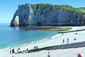 A coastal scene with a prominent white cliff formation and a beach with people. - Apartment in Normandy near Pebble Beach (Fécamp)