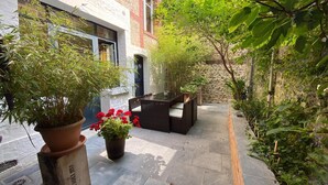 A courtyard with a seating area, potted plants, and a stone wall. - Apartment in Normandy near Pebble Beach (Fécamp)