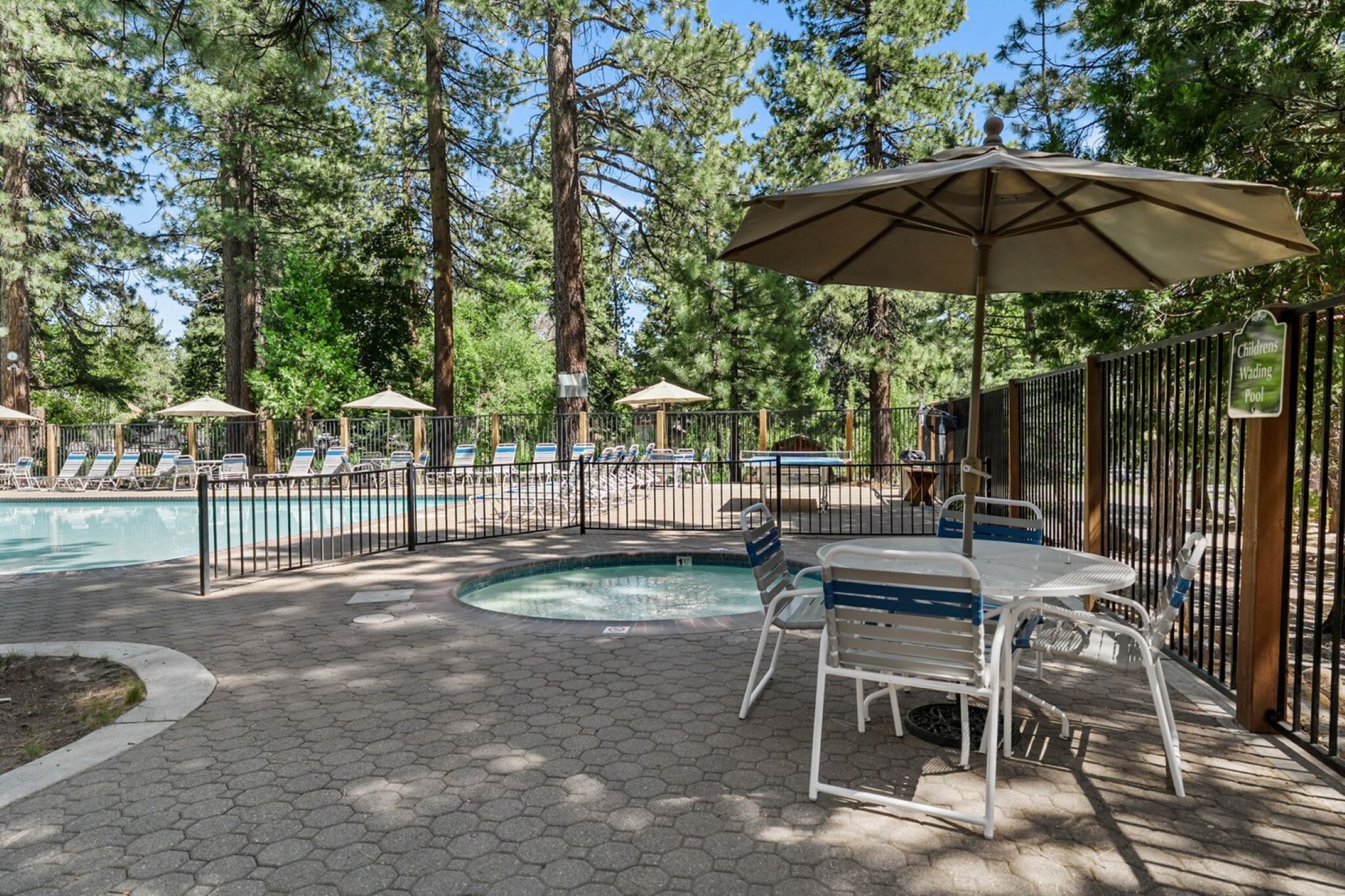 A pool area with lounge chairs, umbrellas, and a small pool.