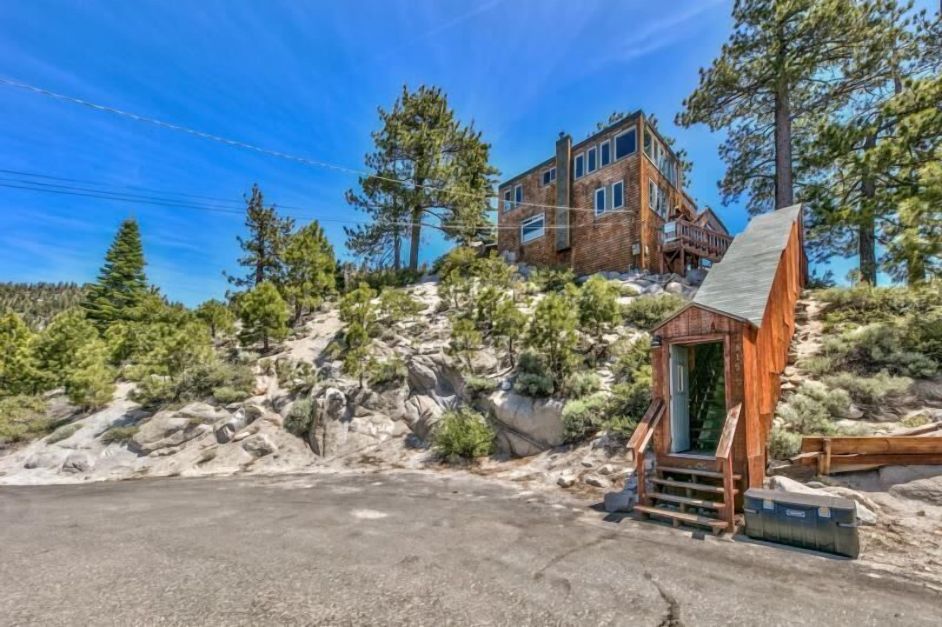 A rustic cabin with a wooden exterior, a small porch, and a steep driveway.