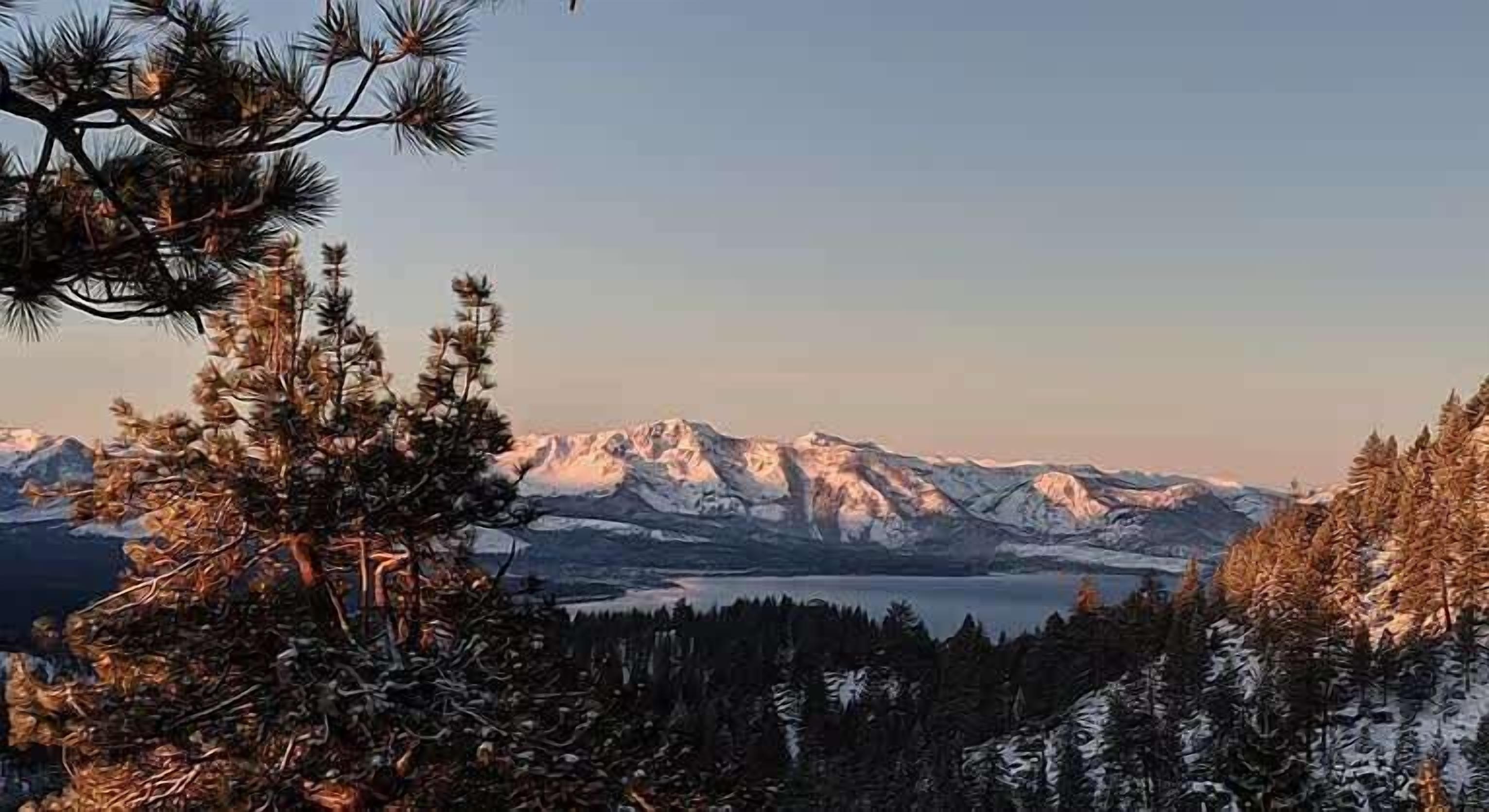 Eine gebirgige Landschaft mit schneebedeckten Gipfeln und einem Gewässer im Hintergrund.