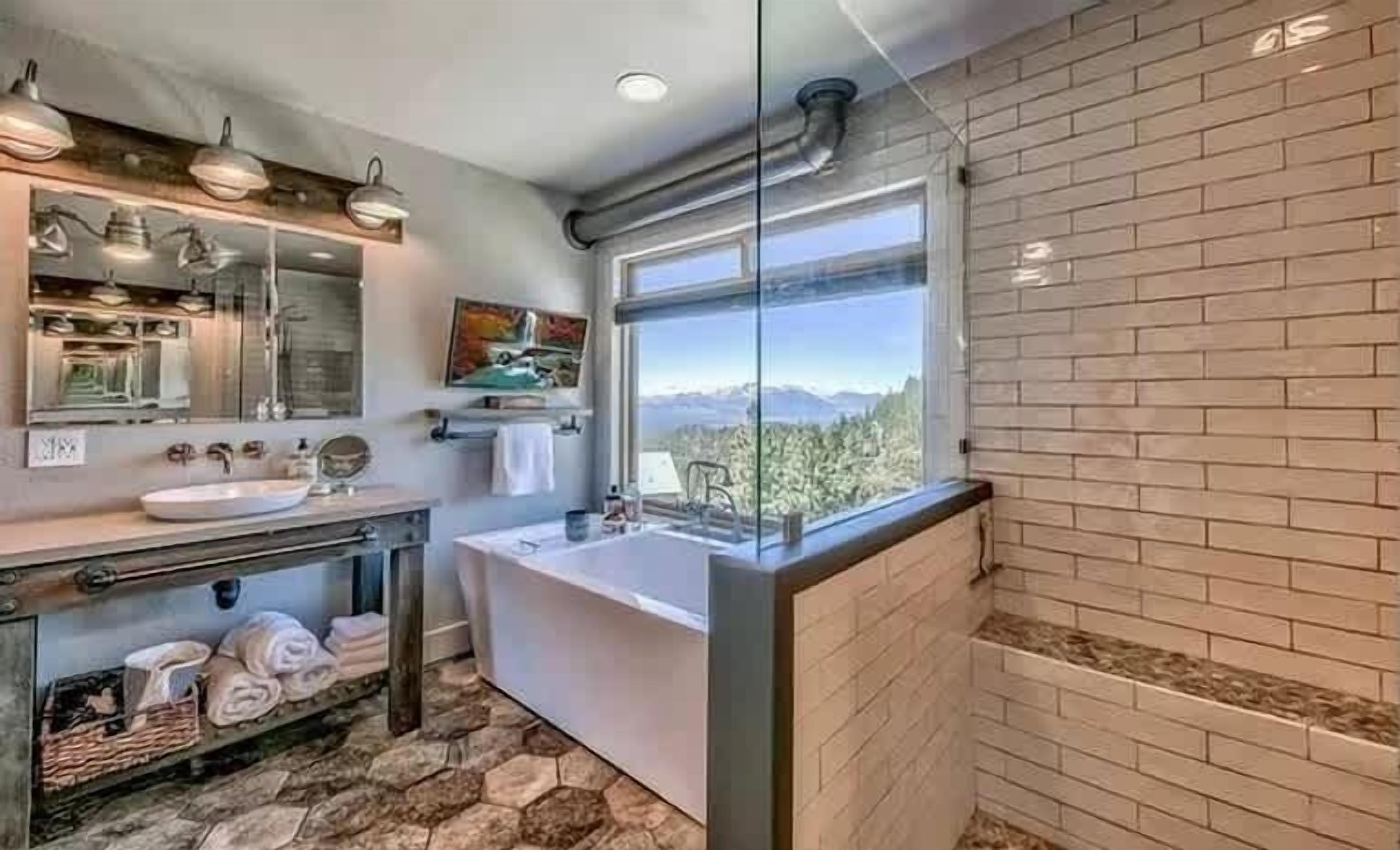 A modern bathroom with a large window, a bathtub, and a vanity with a mirror.