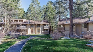 A two-story motel with a central walkway, surrounded by pine trees and a well-maintained lawn. - Horizons Bliss - Near Year-round Activities! (Mammoth Lakes)