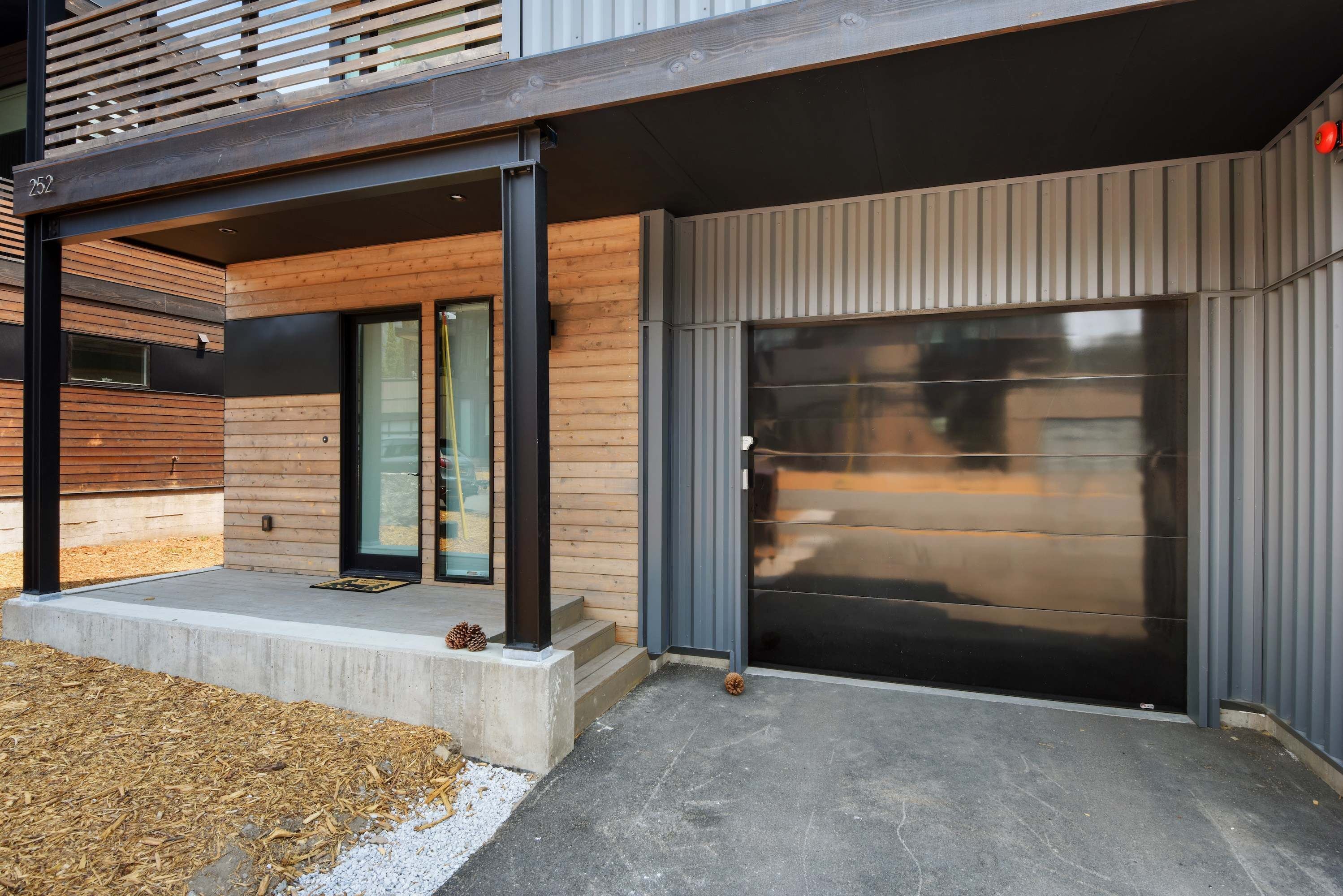 A modern building with a large sliding glass door, a concrete porch, and a wooden exterior.