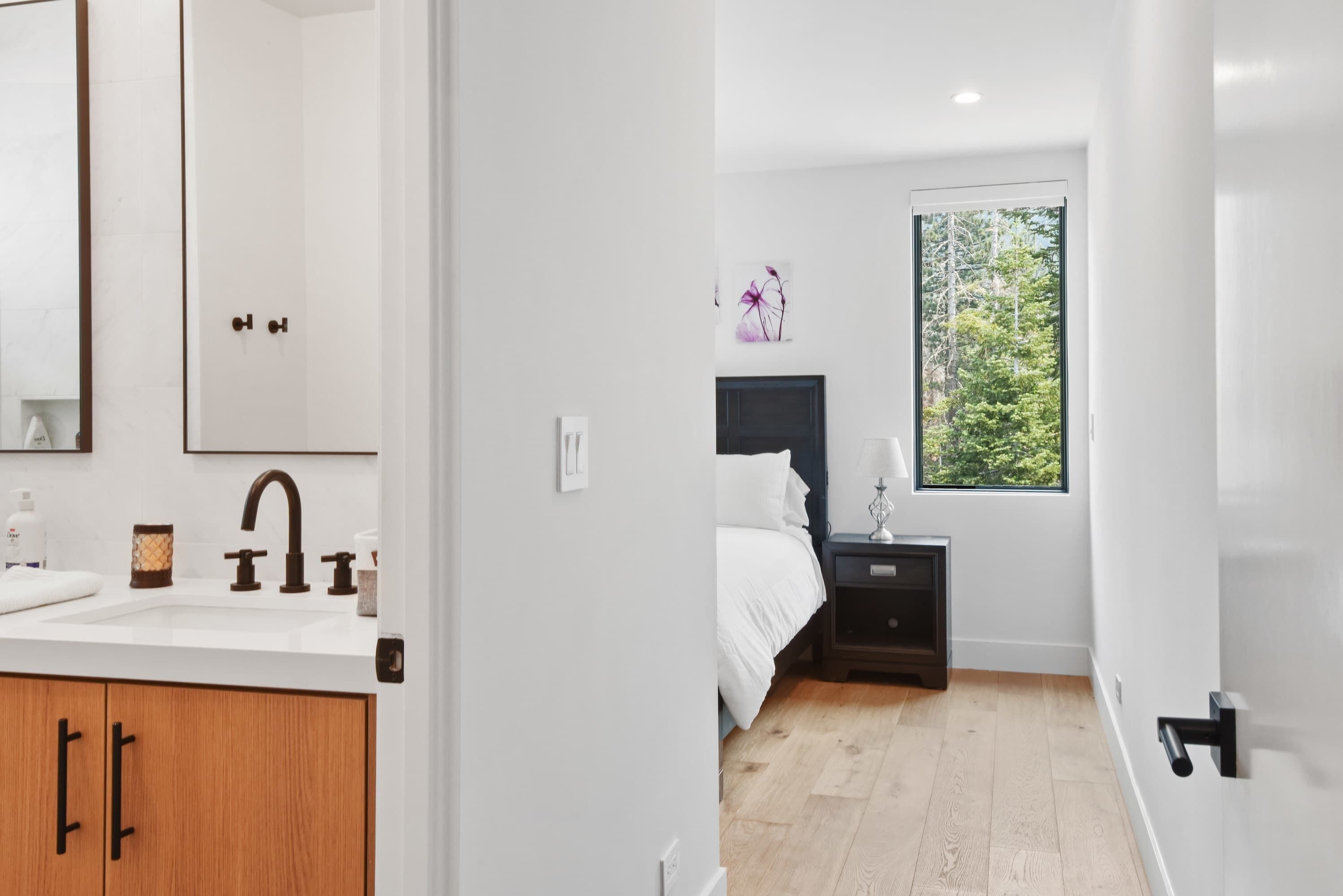 A modern bathroom with a white sink, wooden cabinets, and a large mirror.