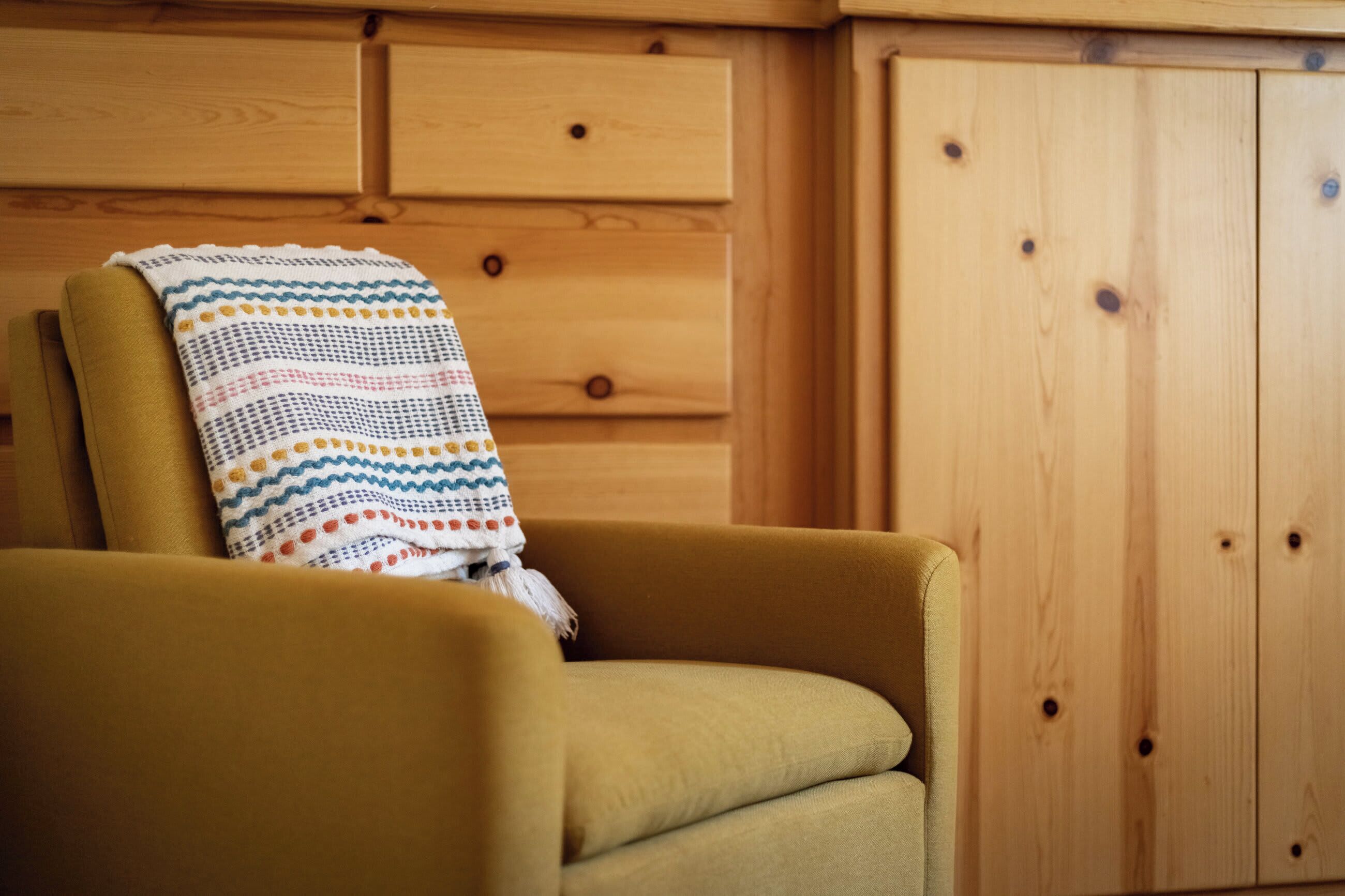 Une pièce avec un meuble en bois et un fauteuil jaune.