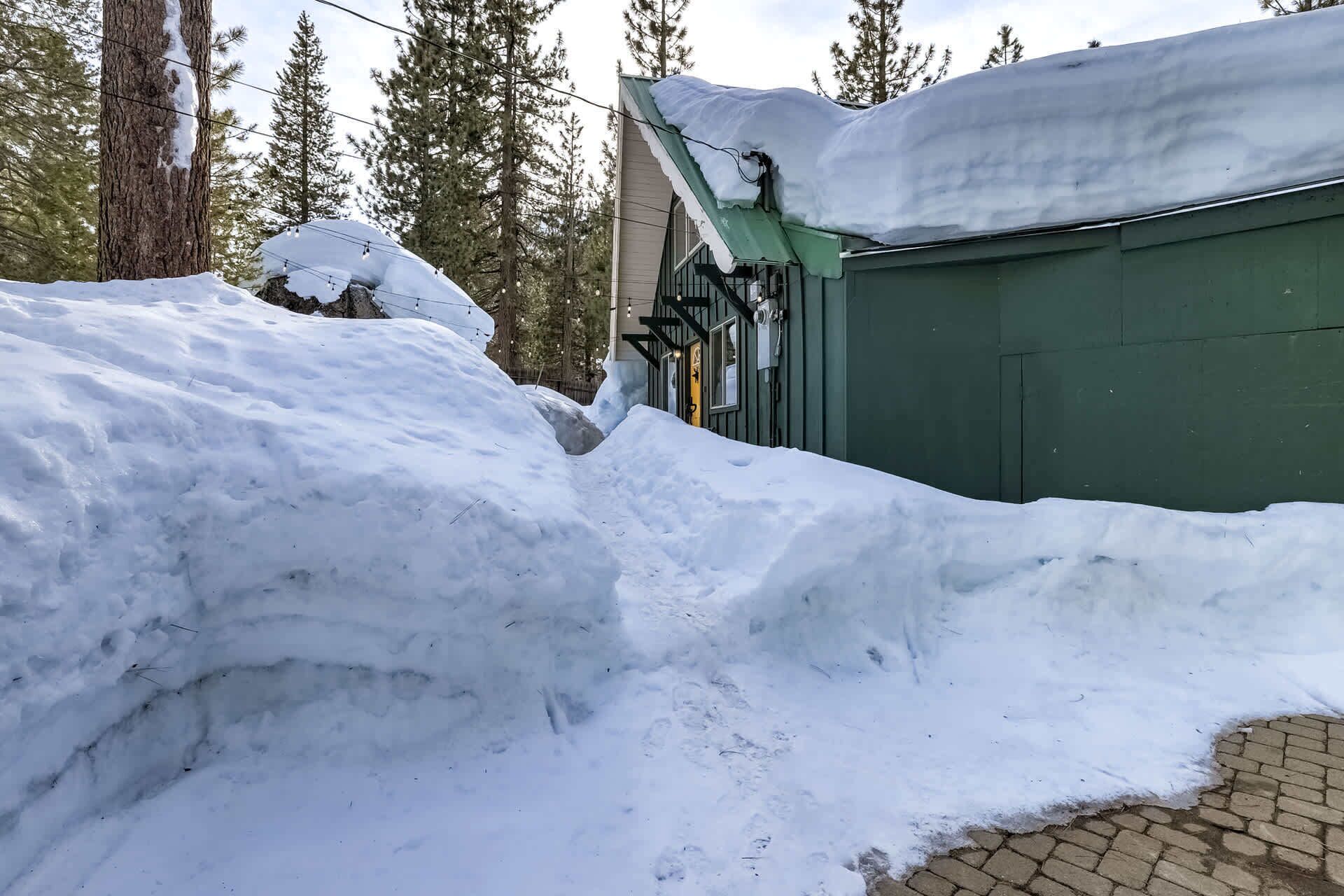 Ett snötäckt landskap med en grön byggnad och en snöhög i förgrunden.