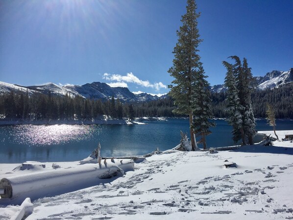 Un paysage enneigé avec un lac, des montagnes et un ciel dégagé.