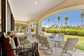 Relax in a tranquil outdoor space with a sofa, chairs, and a bed, surrounded by lush tropical views.