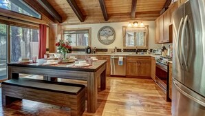 Een ruime keuken met houten balken, een groot eiland, roestvrijstalen apparatuur en uitzicht op de omgeving.
