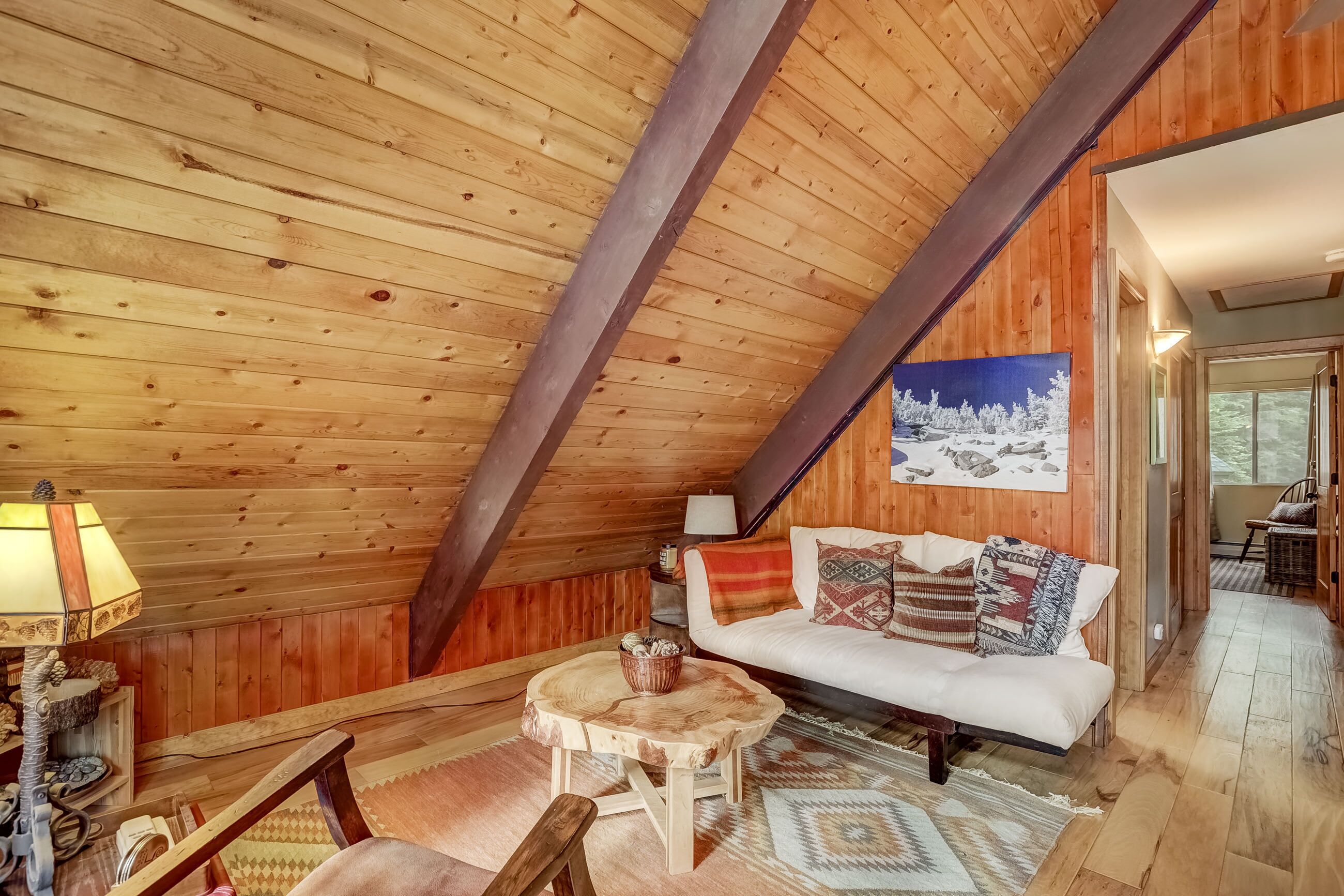 Un interior de madera acogedor con un sofá blanco, una mesita redonda y una lámpara.