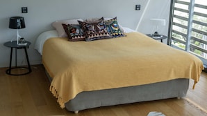 Un dormitorio con cama, mesita de noche, lámpara y ventana con persianas.