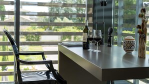 Un comedor moderno con barra, una silla y vista a la vegetación a través de amplios ventanales.