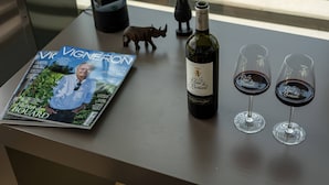 Una revista, una botella de vino y dos copas de vino sobre una mesa.