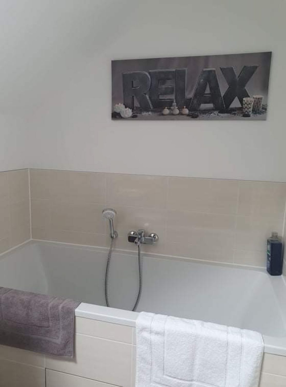 A bathroom with a bathtub, a shower, and a towel rack.