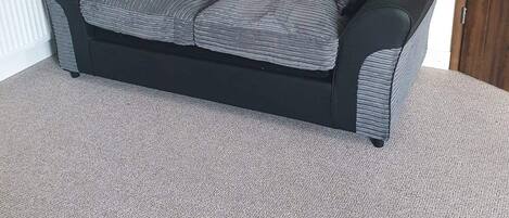 A grey sofa with a black frame in a room with a sloped ceiling and a radiator.