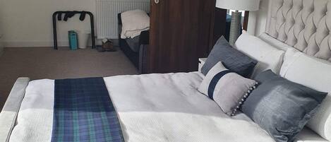 A bedroom with a bed, a nightstand, a lamp, a radiator, and a door.
