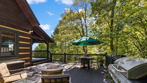 Une terrasse en bois avec des meubles d’extérieur, un barbecue et une table avec un parasol.