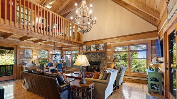 Un vaste salon doté d’une cheminée, de parquets en bois et d’un balcon agrémenté d’une balustrade en bois.