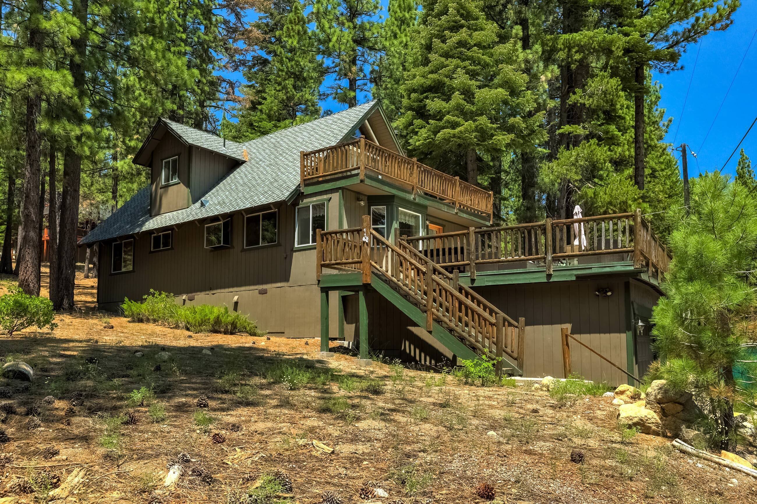 A cabin with a two-story deck and a steep staircase.
