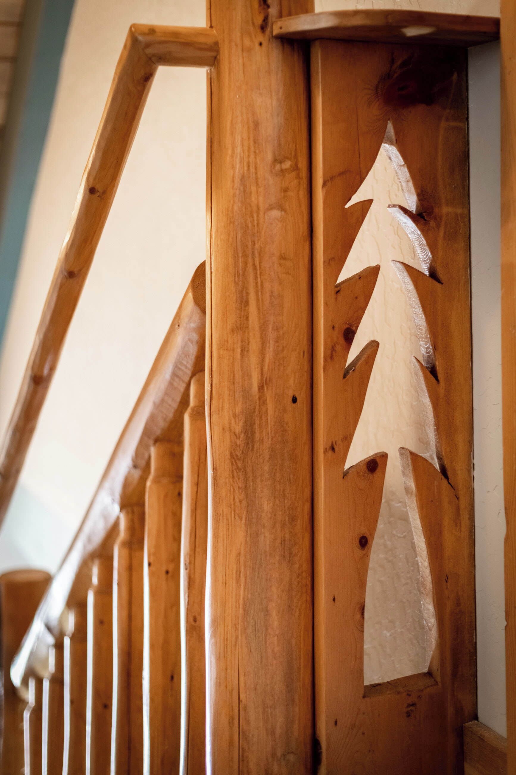A wooden staircase with a carved tree design on the railing.