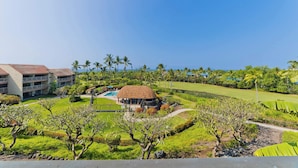 Un resort con piscina, una construcción de techo de paja y un campo de golf.