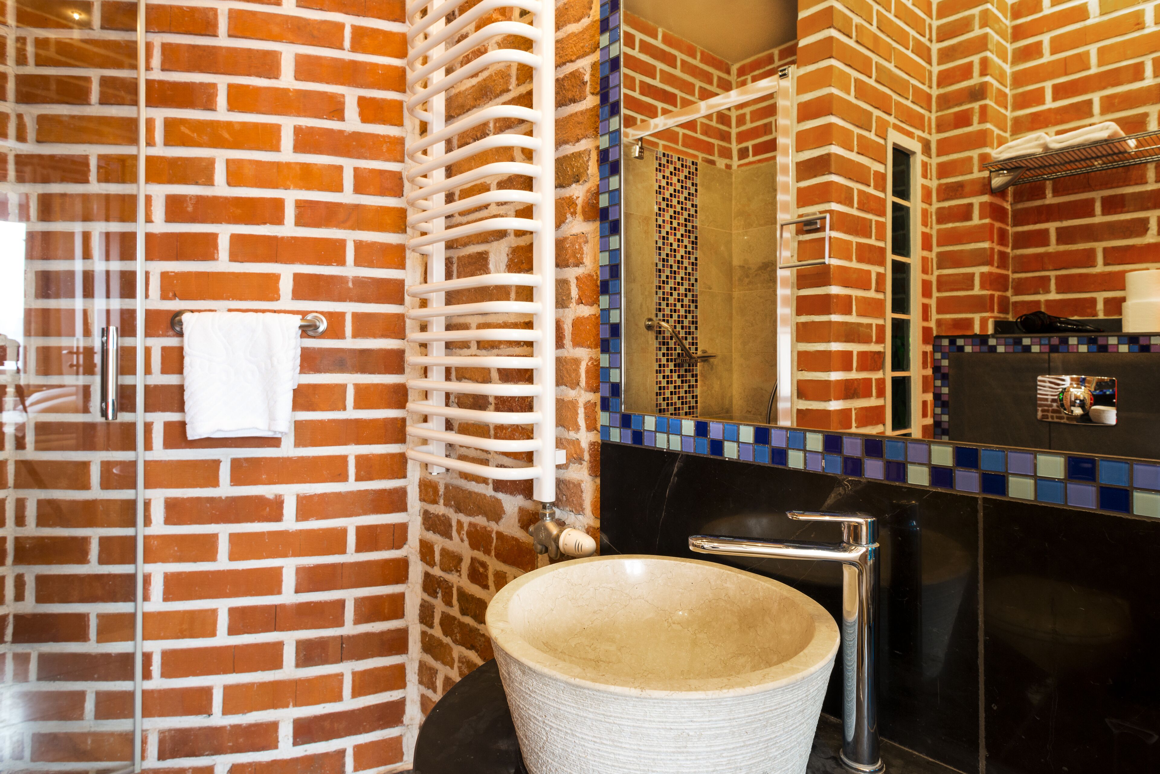 A bathroom with a large, round sink, a modern faucet, and a tiled shower area.